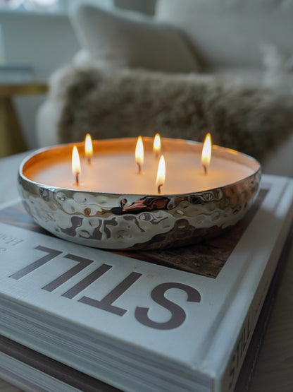 Candle in a metallic bowl with multiple flames on top of a book titled &