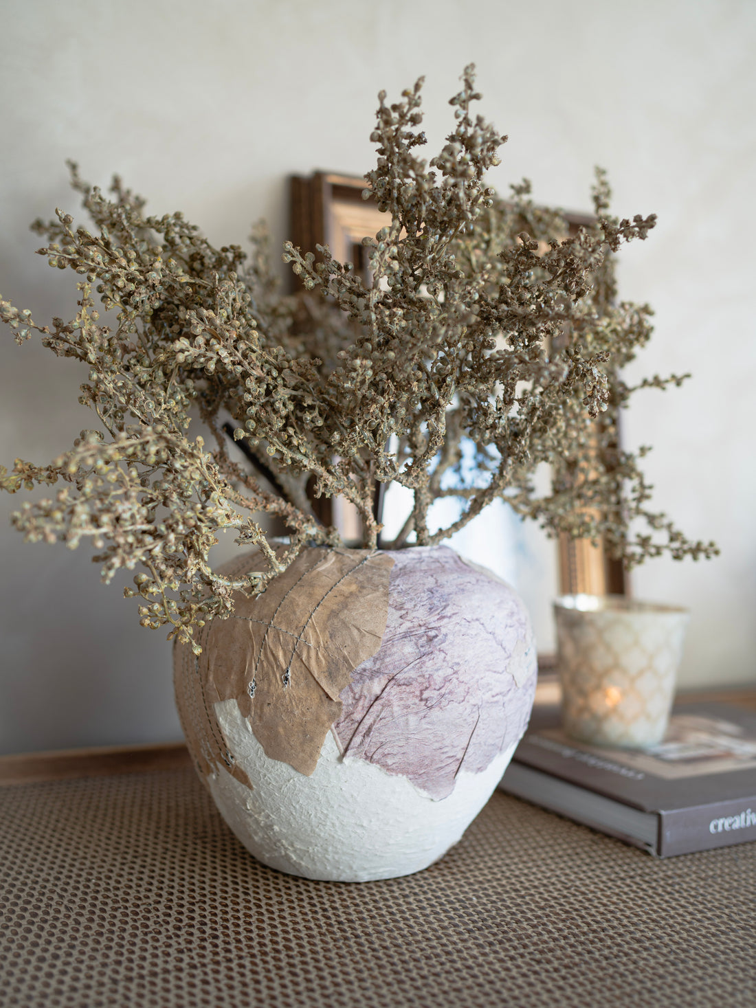 Decorative unearthed ceramic vase with dried branches on a textured surface