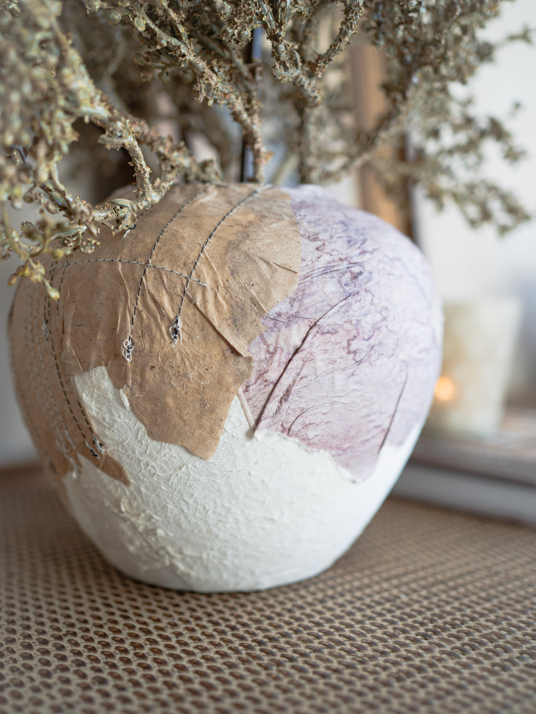 Decorative spherical vase with leaf patterns on a textured surface