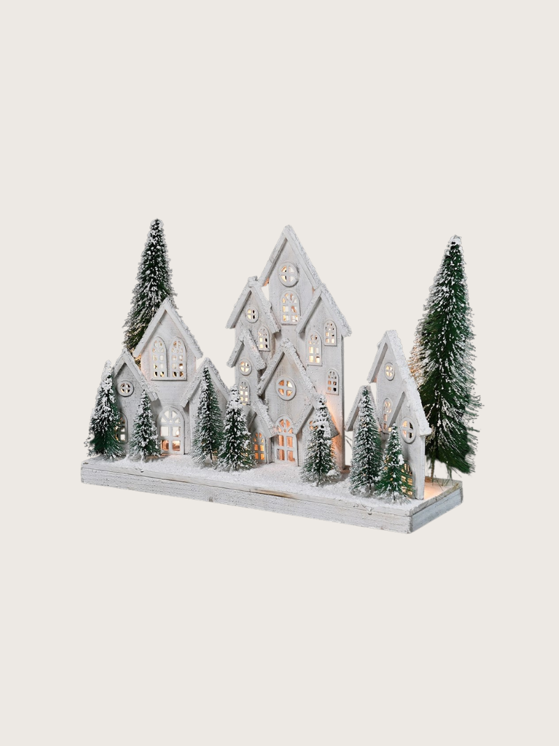 Decorative model of a snowy village with houses and trees on a white background