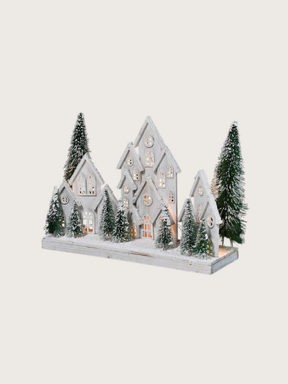 Decorative model of a snowy village with houses and trees on a white background