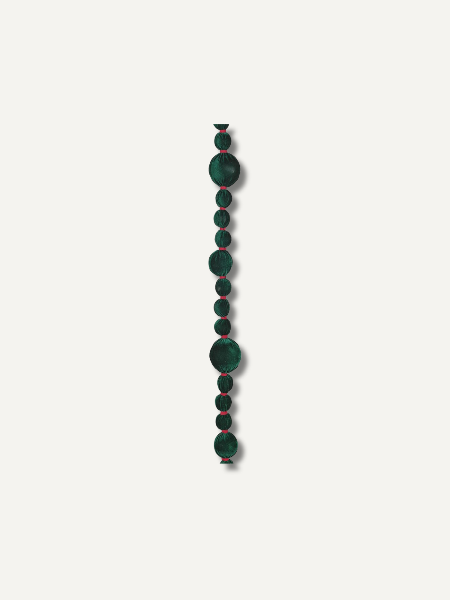 A single strand of dark green bobble beads garland with subtle red edges, arranged vertically against a solid off-white background.