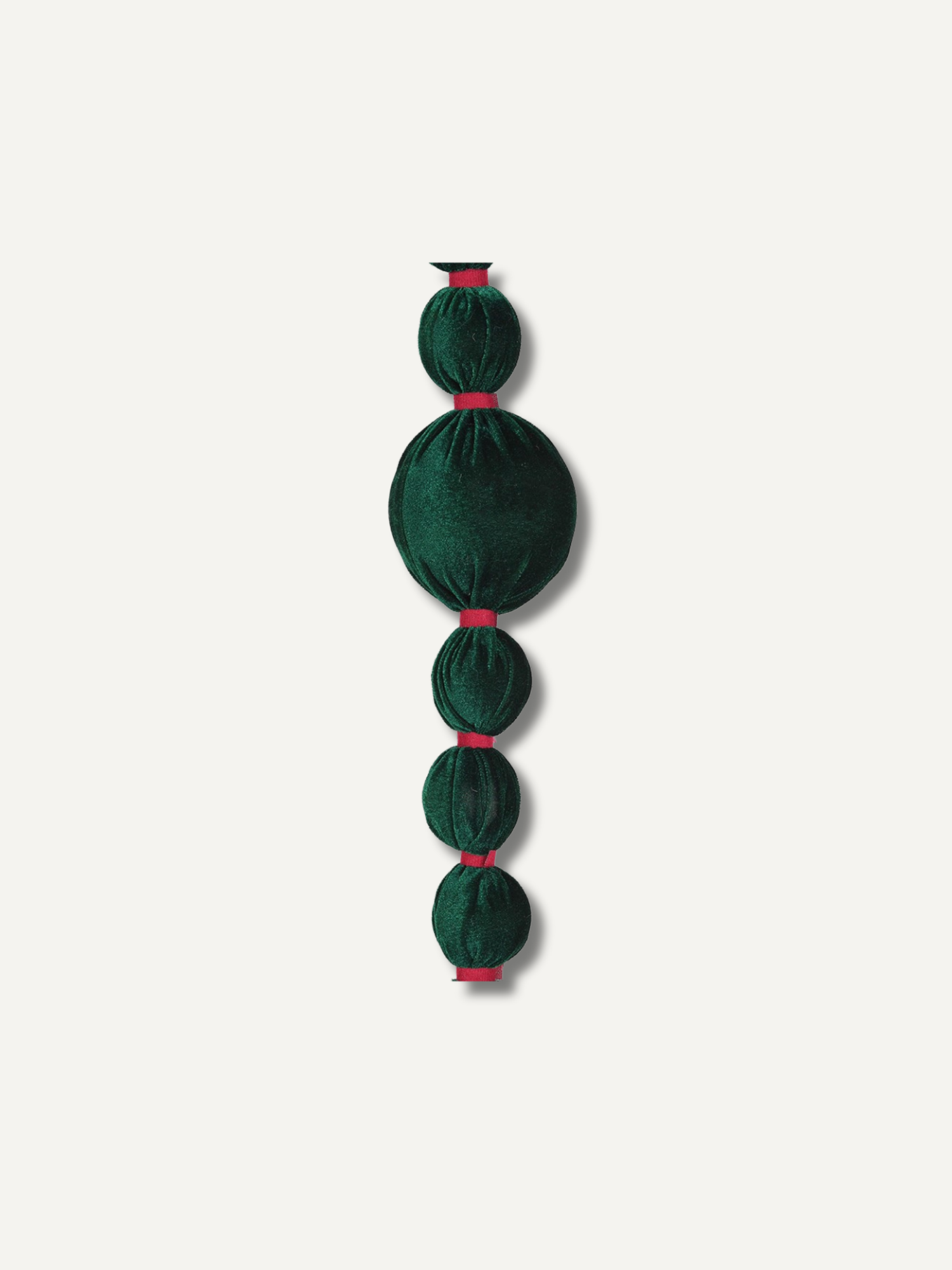 A dark green velvet beaded bobble garland with alternating oval and round beads, accented by thin red ribbons at the connections, shown against a plain off-white background.