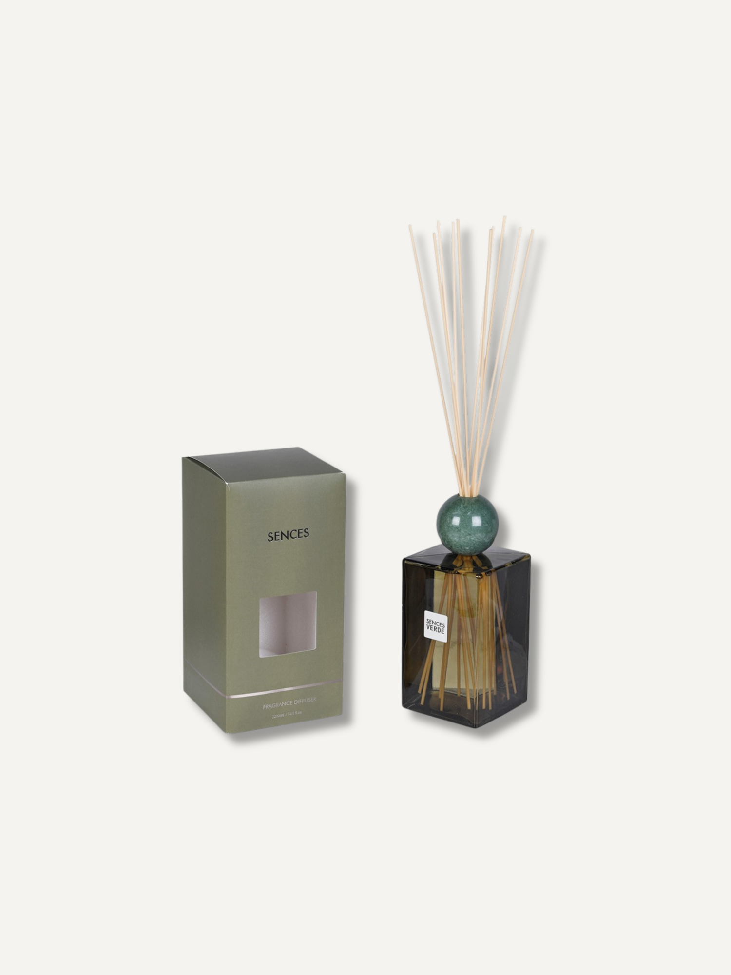 A reed diffuser bottle with a dark green glass body, a round green bead, and natural reed sticks, shown next to its olive green packaging box on a light beige background.