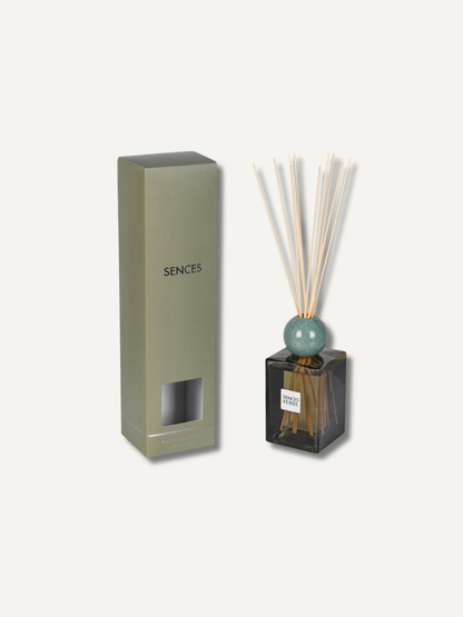 A reed diffuser set with a tall olive green rectangular box labeled &