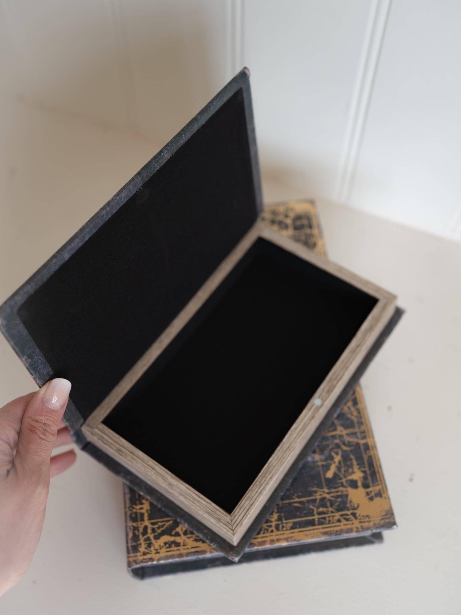 Open storage book box with gold design on a white surface