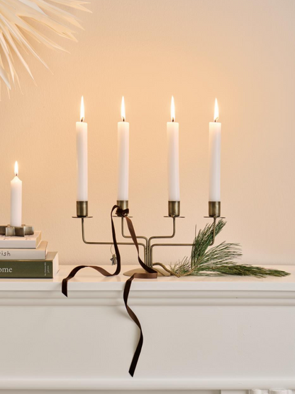 Candle holder candelabra with lit candles on a white surface against a beige wall