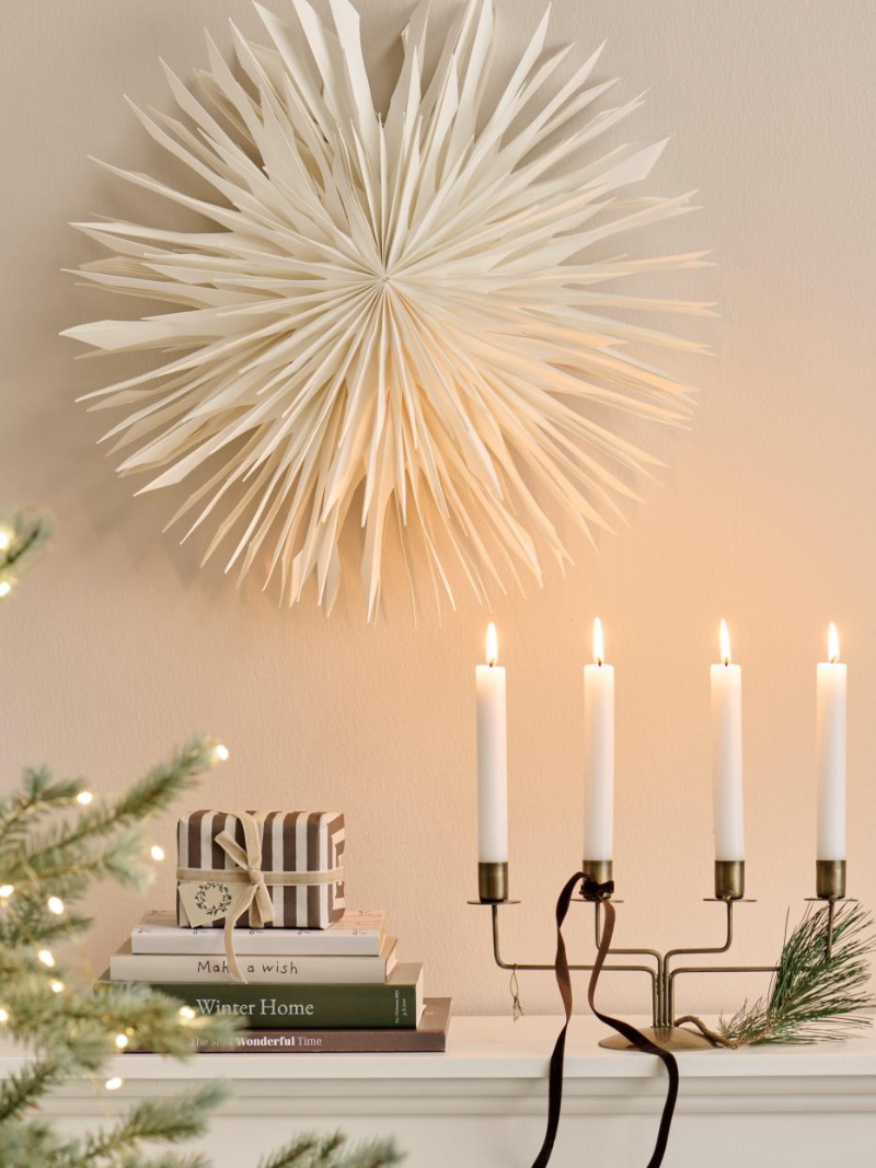 Decorative wall light fixture with candles and books on a mantel