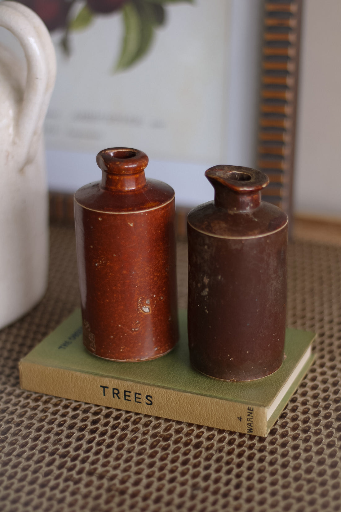 Two brown ceramic bottles on a green book titled &