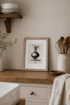 Kitchen counter with framed artwork, wooden spoons, and a vase.