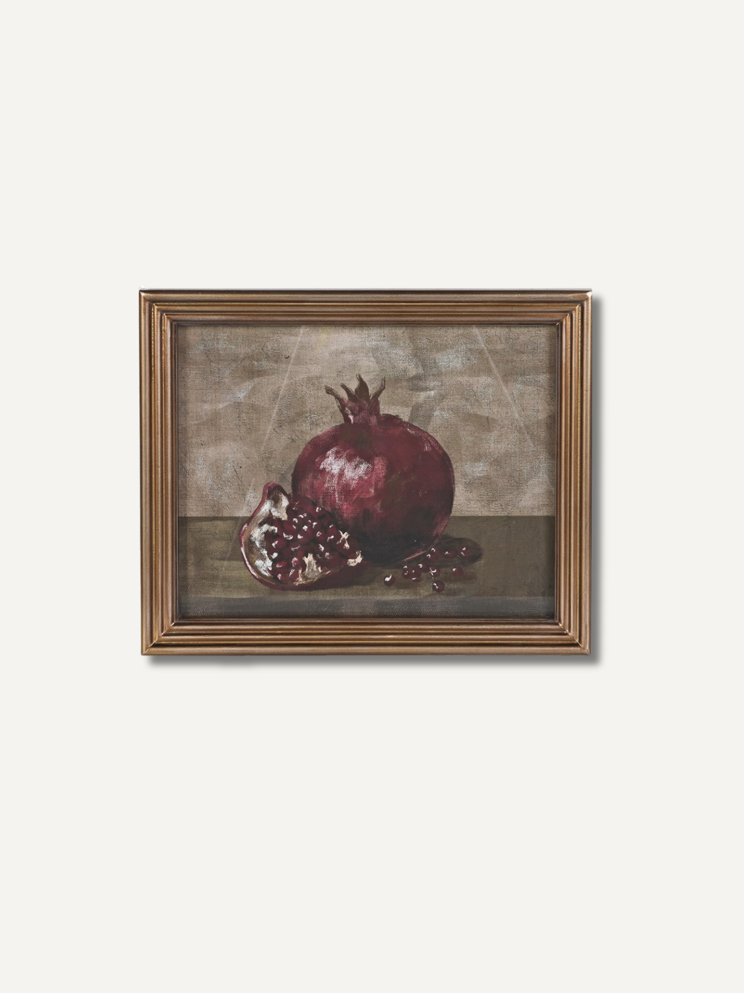 A framed still life painting of a pomegranate, featuring a whole and halved pomegranate on a dark surface against a textured beige-brown background, enclosed in a gold-toned frame.