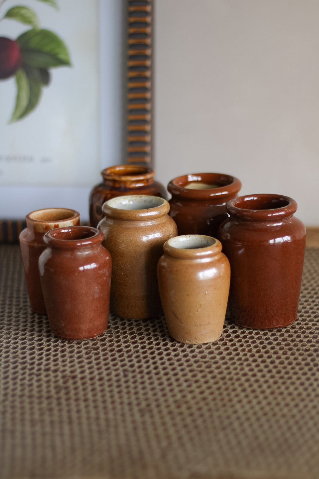 Collection of brown ceramic jars on a textured surface with a blurred background