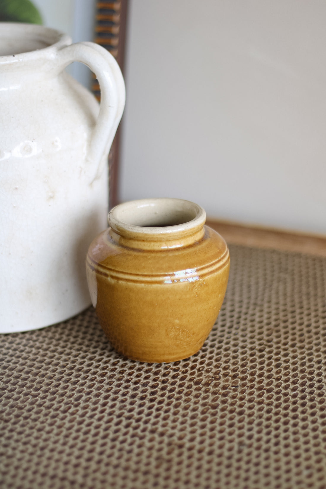 Two ceramic jars, one white and one brown, on a textured surface.