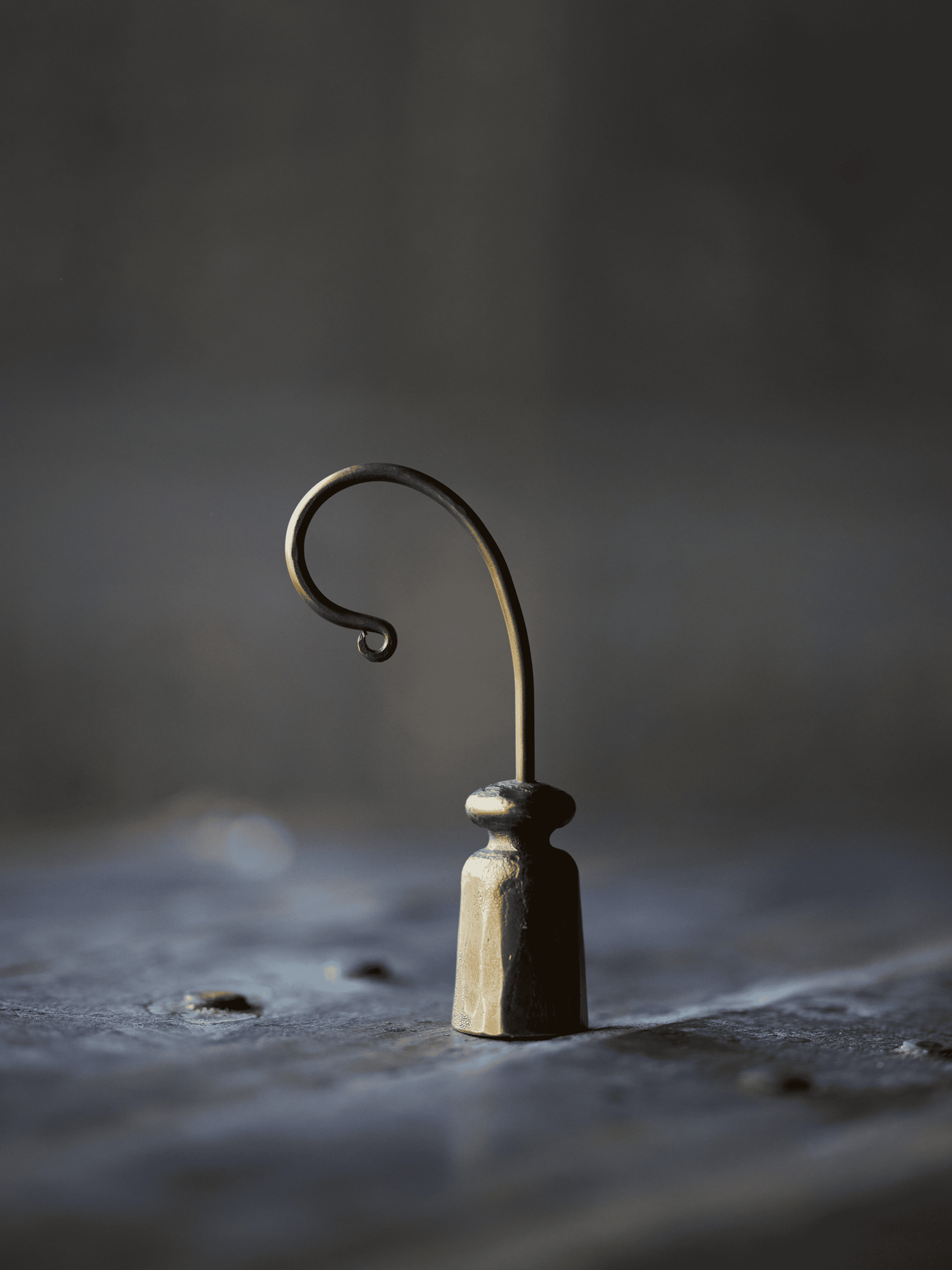 Small vintage gold style candle snuffer on a textured surface with a dark background
