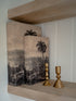 Decorative boxes with landscape and palm tree design on a wooden shelf.