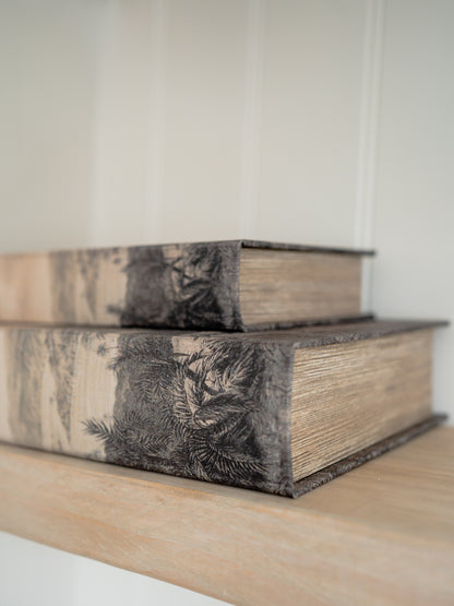 Two decorative storage books with floral patterns on a wooden surface.