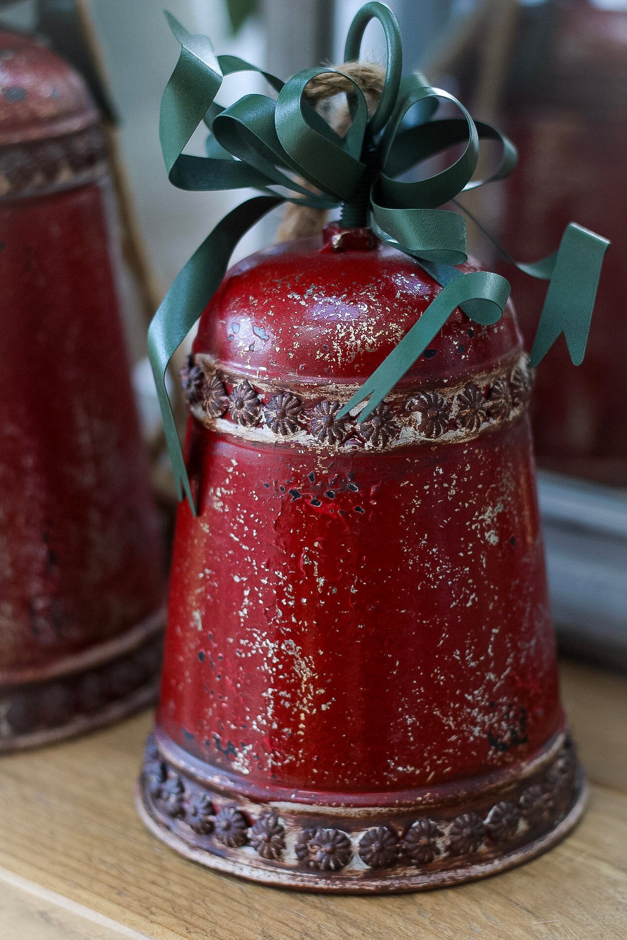 Red ceramic bell with green ribbon on a wooden surface