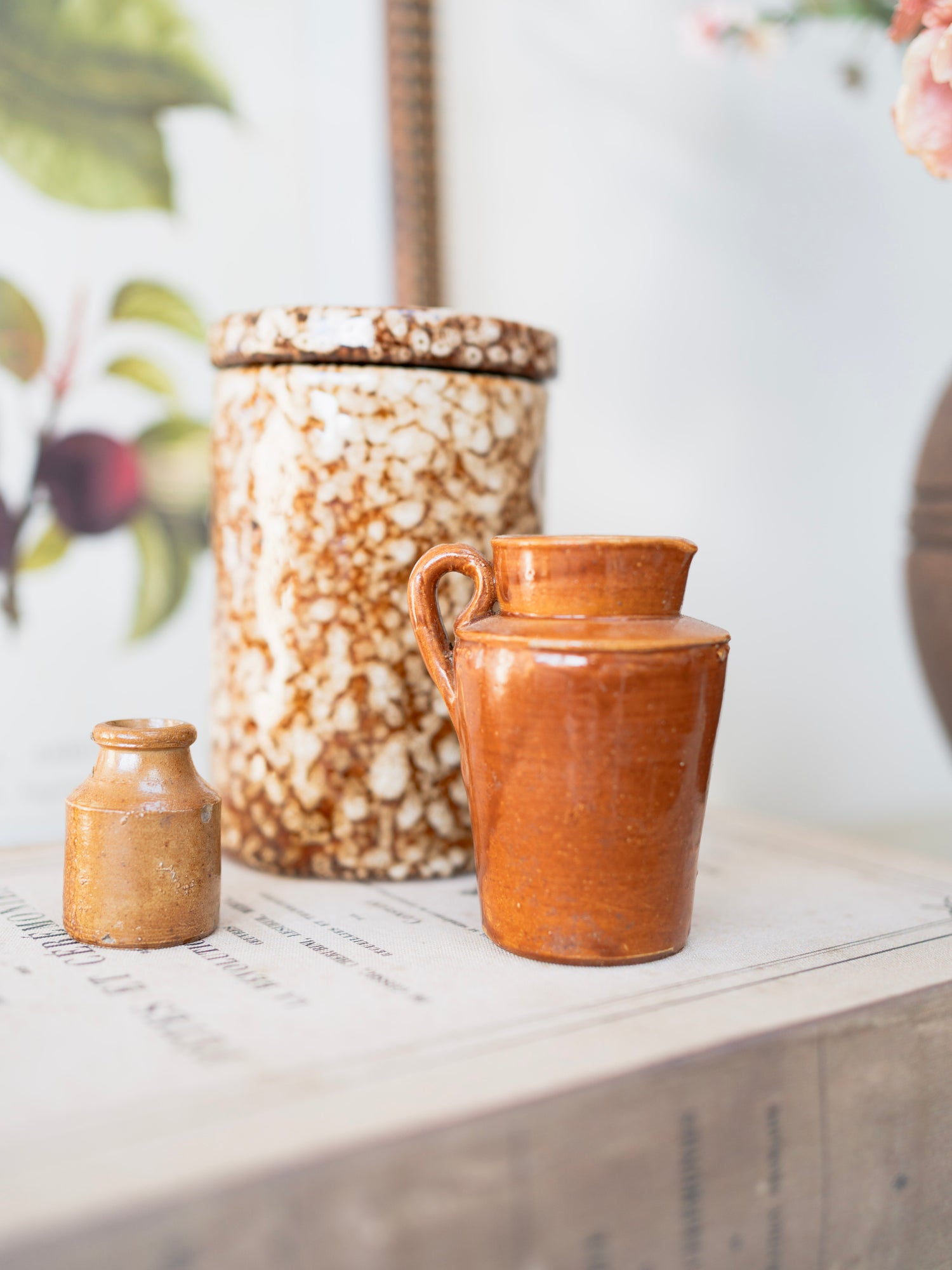 Three ceramic vintage jugs of different sizes on a surface with a blurred background