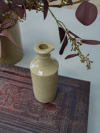 Vintage-style ceramic bottle on a textured surface with decorative elements