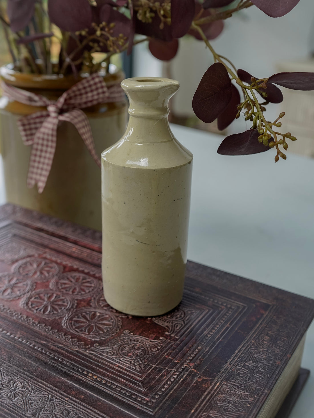 cream ceramic bottle on a textured surface with blurred background