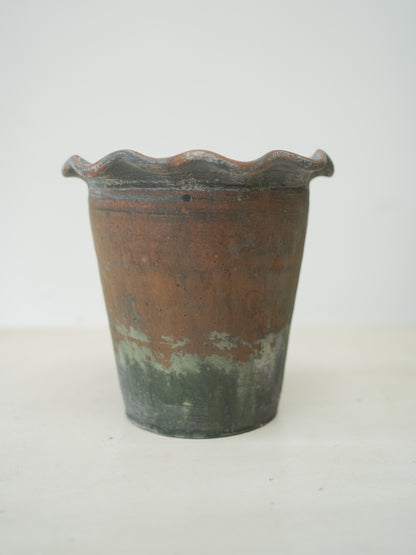 Terracotta plant pot with a wavy rim on a white background