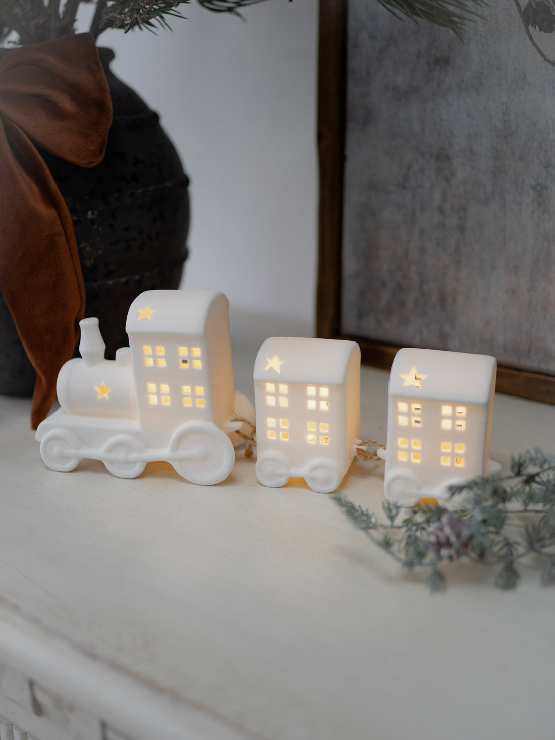 Set of three white ceramic house-shaped lights on a surface with a blurred background