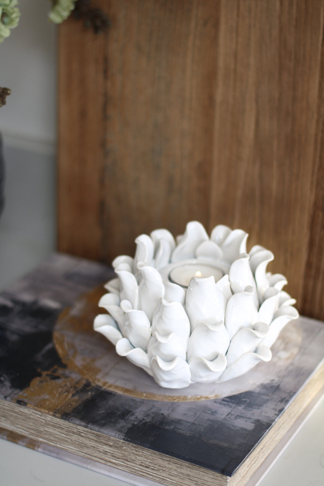 White flower-like ceramic candle holder on a wooden surface with a blurred background