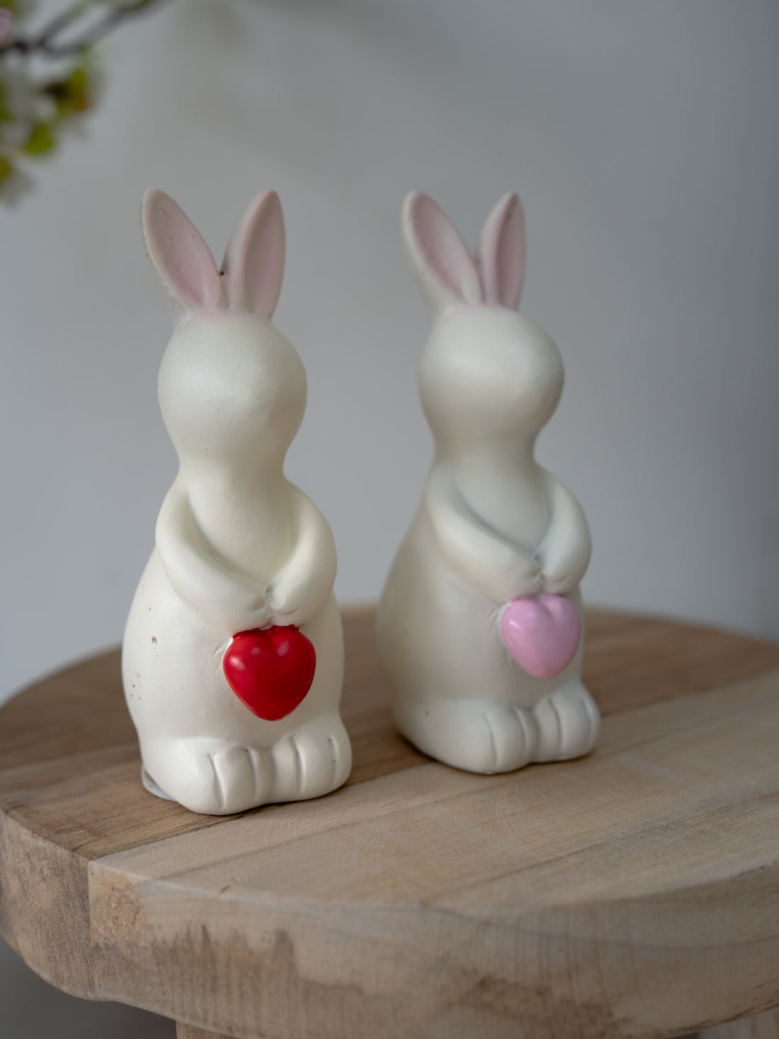 Two ceramic rabbit figures with red and pink heart shapes on a wooden surface.