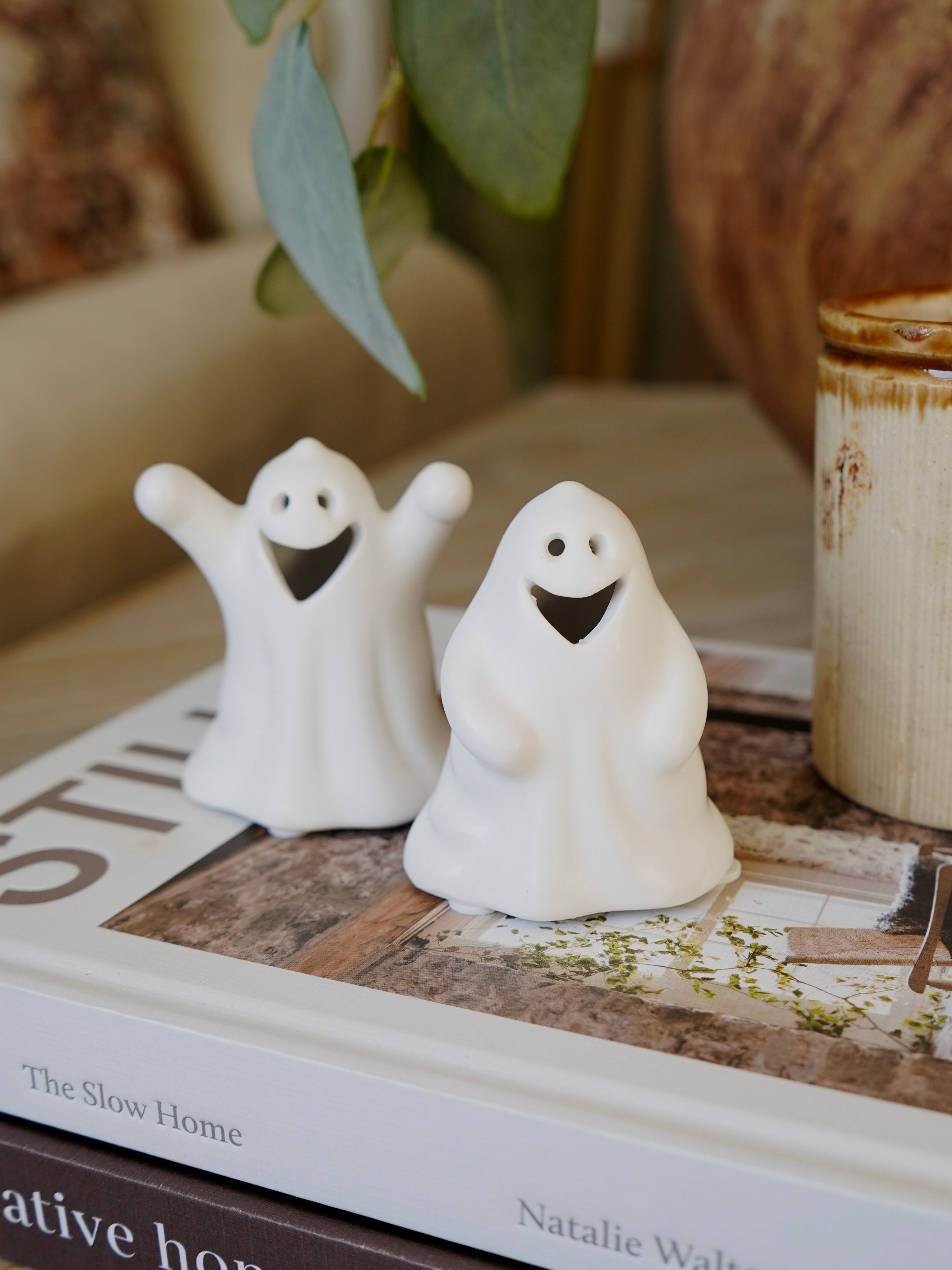 Two white ghost figurines on a book with a blurred background