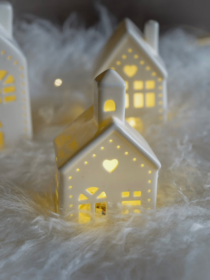 Decorative ceramic houses with cut-out patterns on a soft white surface