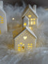 Decorative ceramic houses with cut-out patterns on a soft white surface