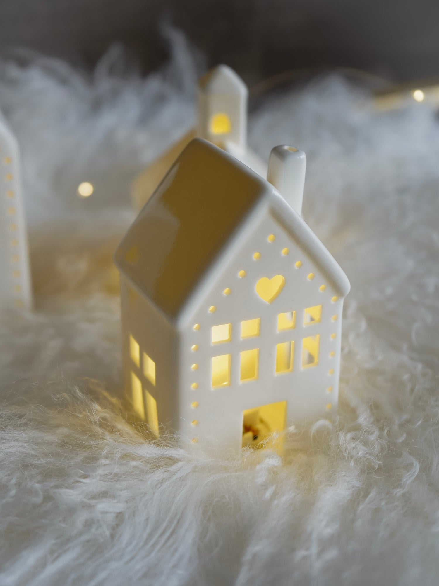 Decorative house-shaped light on a soft white surface with a dark background