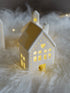 Decorative house-shaped light on a soft white surface with a dark background