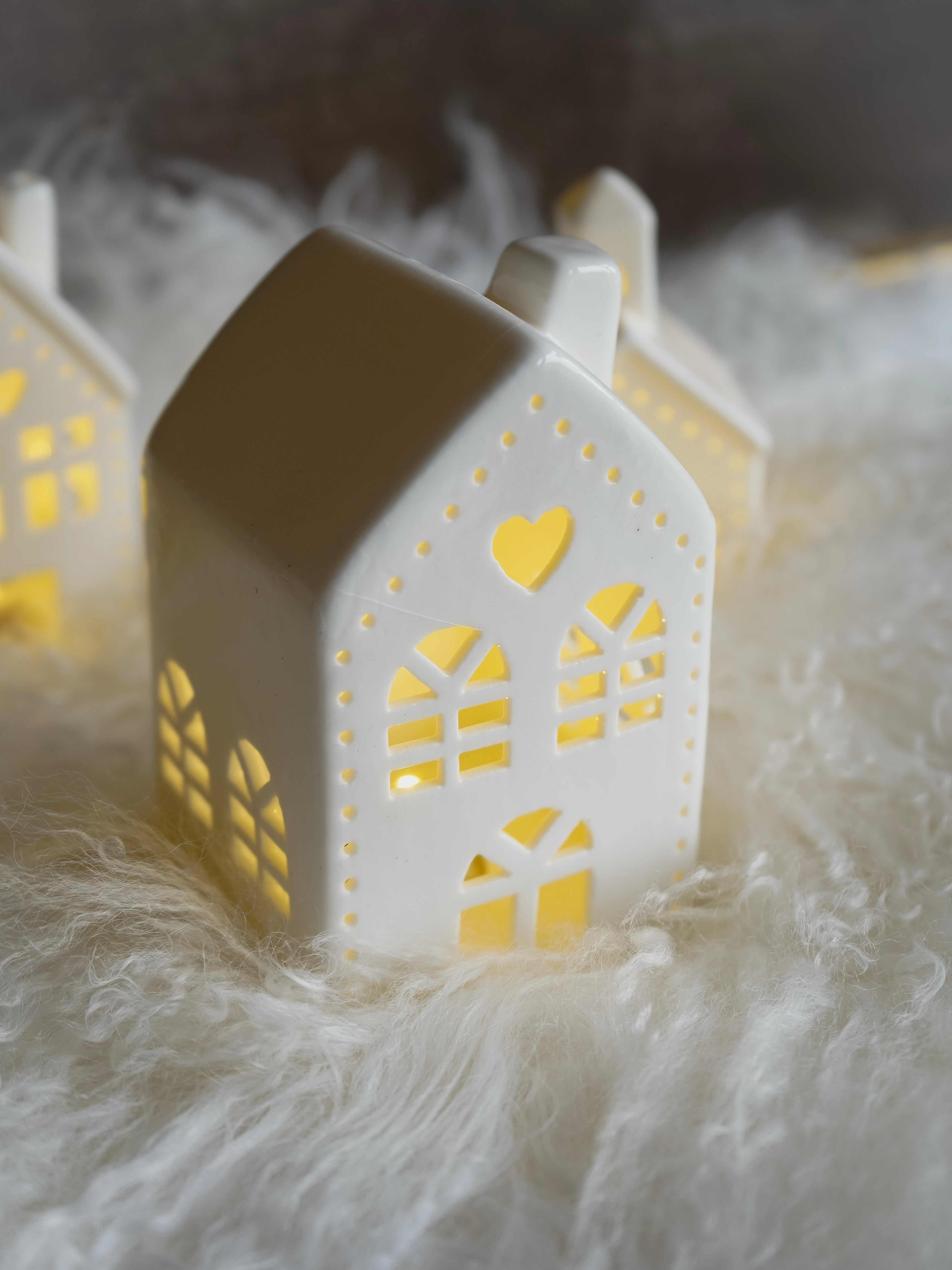 White house-shaped lanterns with cut-out patterns on a soft white surface