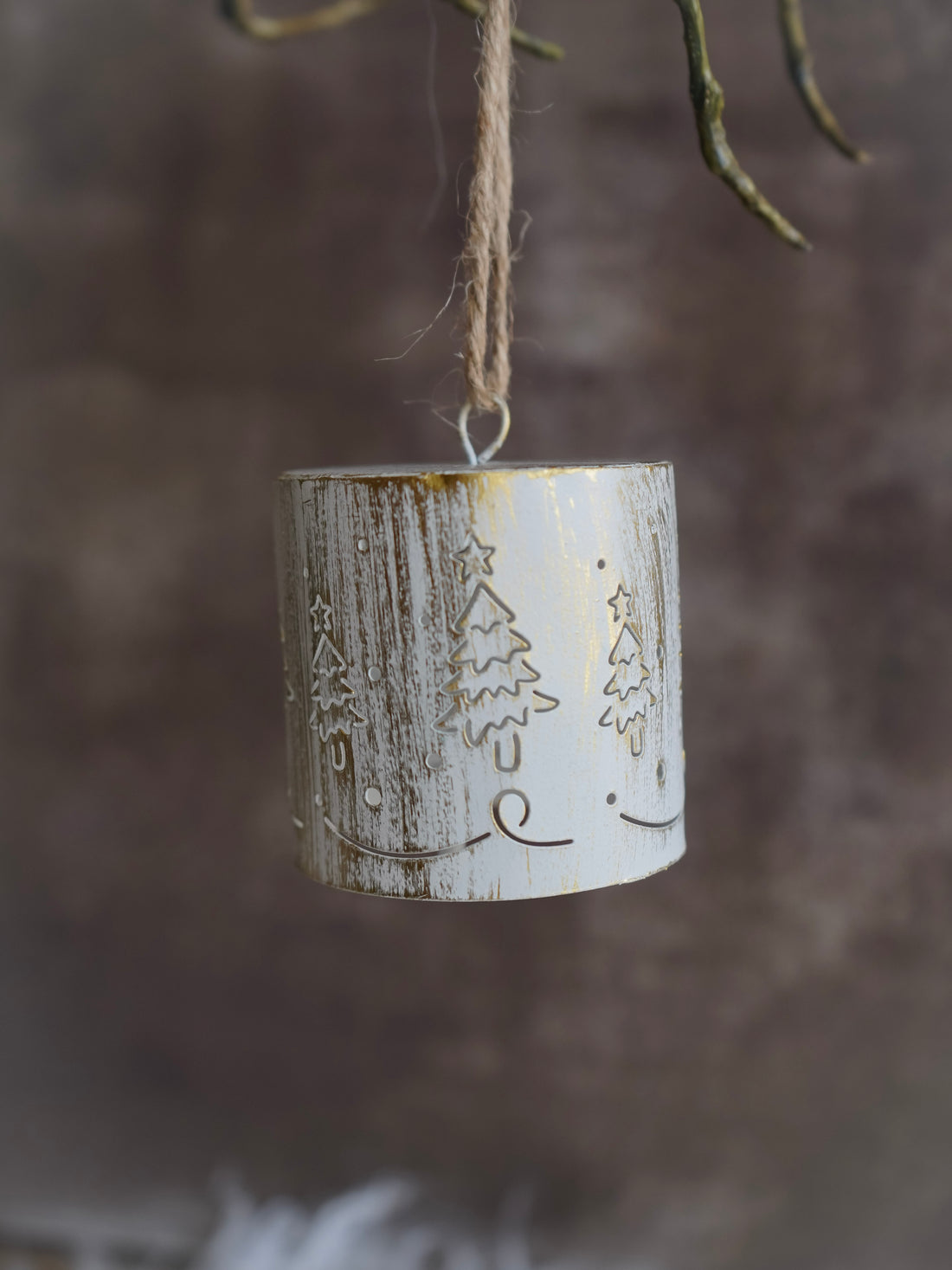Decorative hanging ornament with winter scene design against a blurred natural background