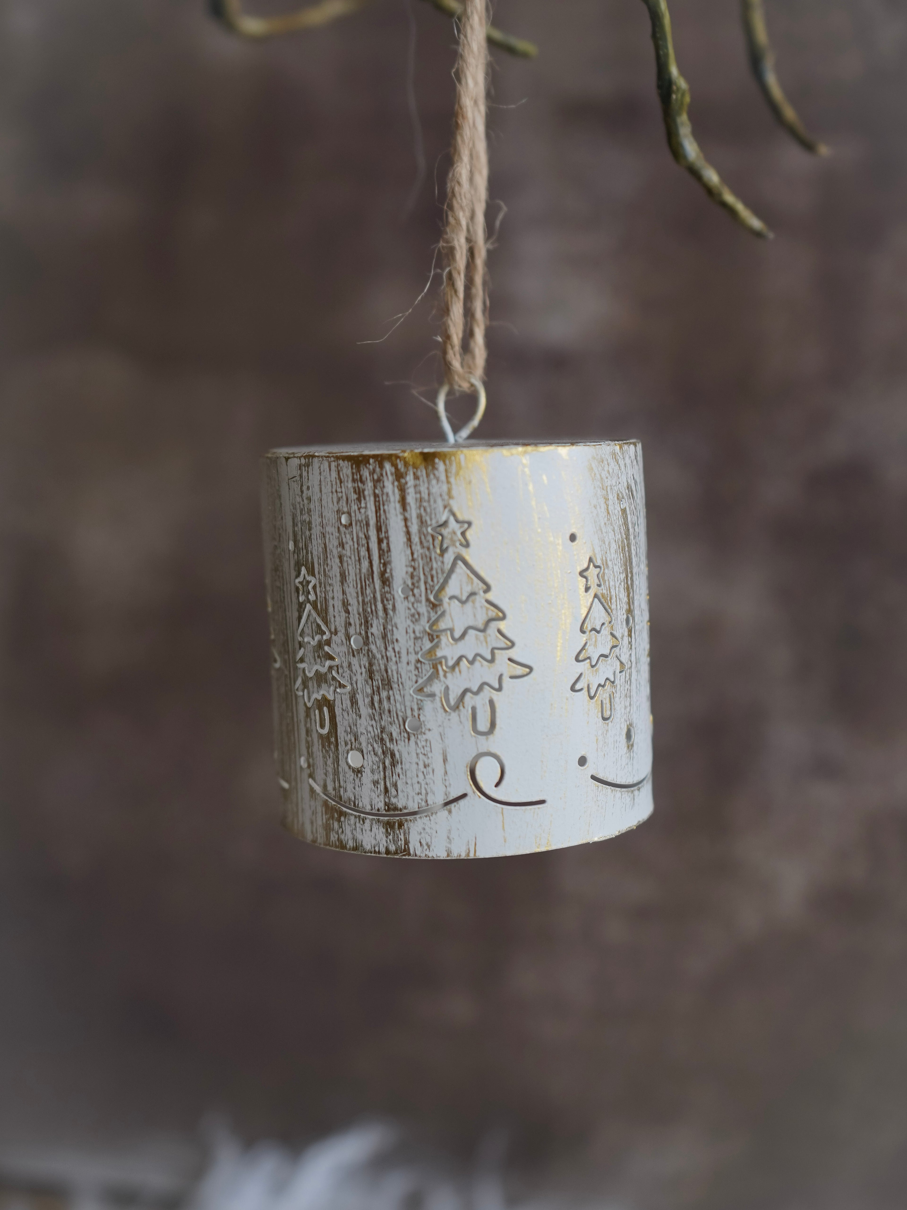Decorative hanging ornament with winter scene design against a blurred natural background