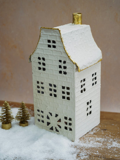 Decorative house-shaped lantern with snow on a neutral background