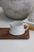 White mottled terracotta pot on a wooden tray with a blurred background