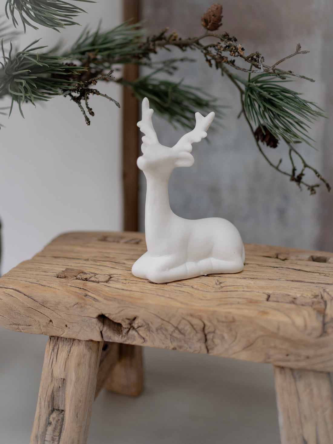 White deer figurine on a wooden surface with a natural background