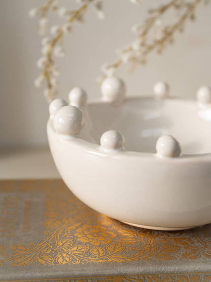 White ceramic bowl with spherical bobble protrusions on a decorative surface