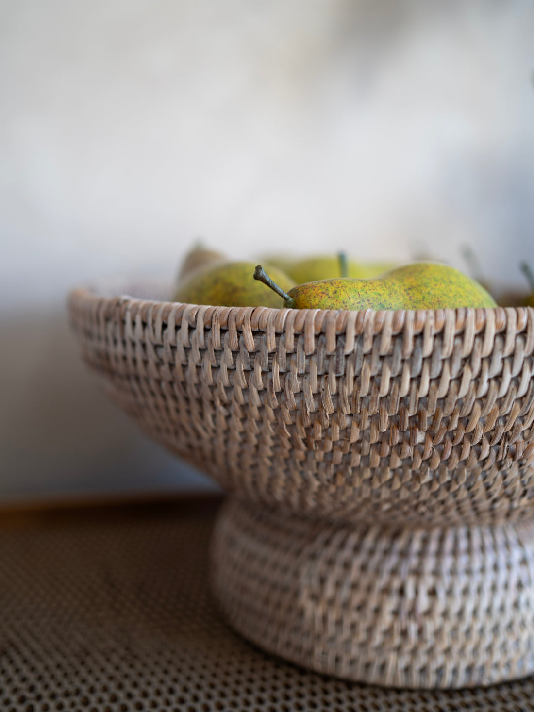 Woven basket with a faux conference pears on a neutral background