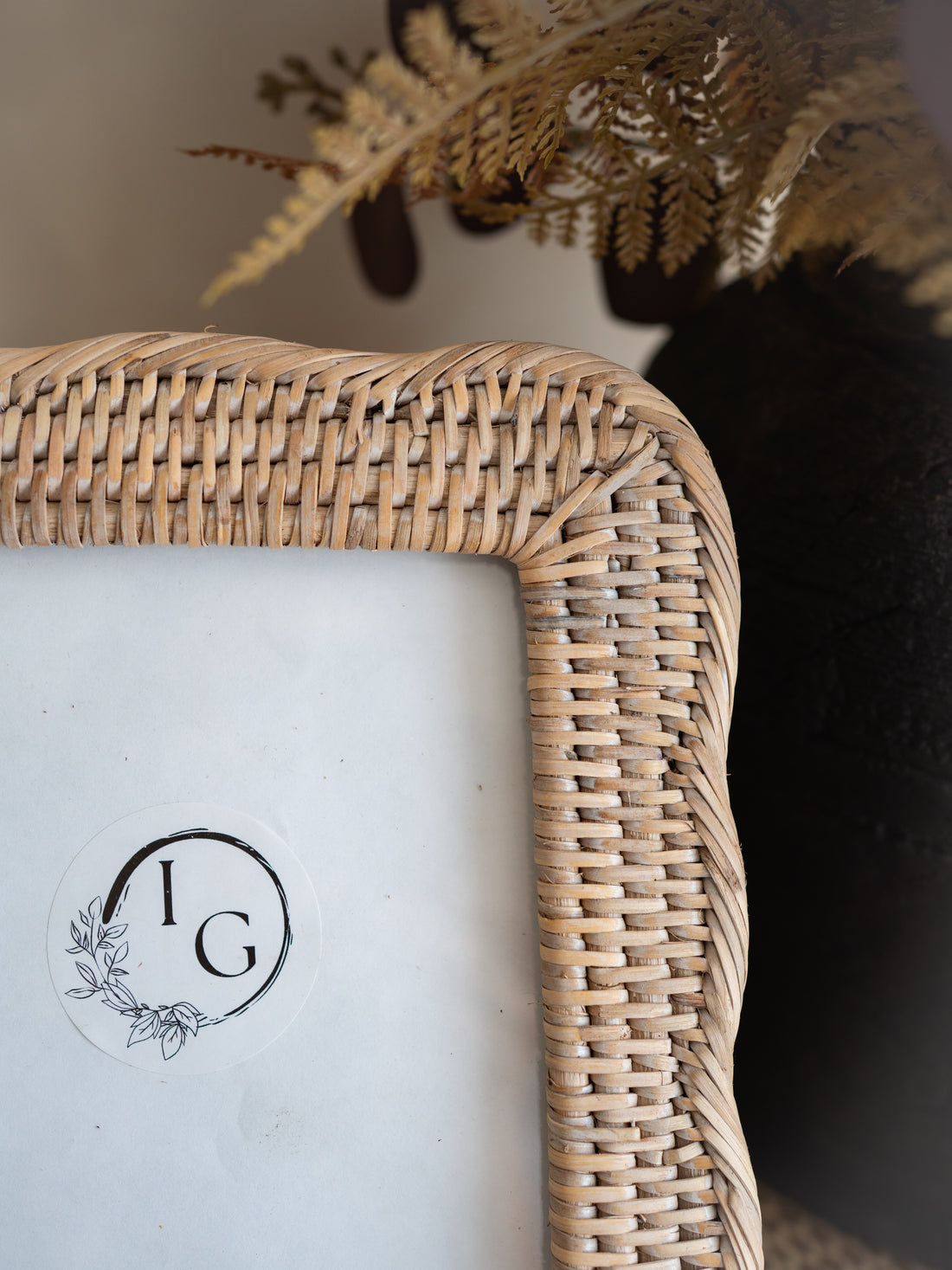 Close-up of a woven natural rattan picture frame corner with a white insert and a circular &