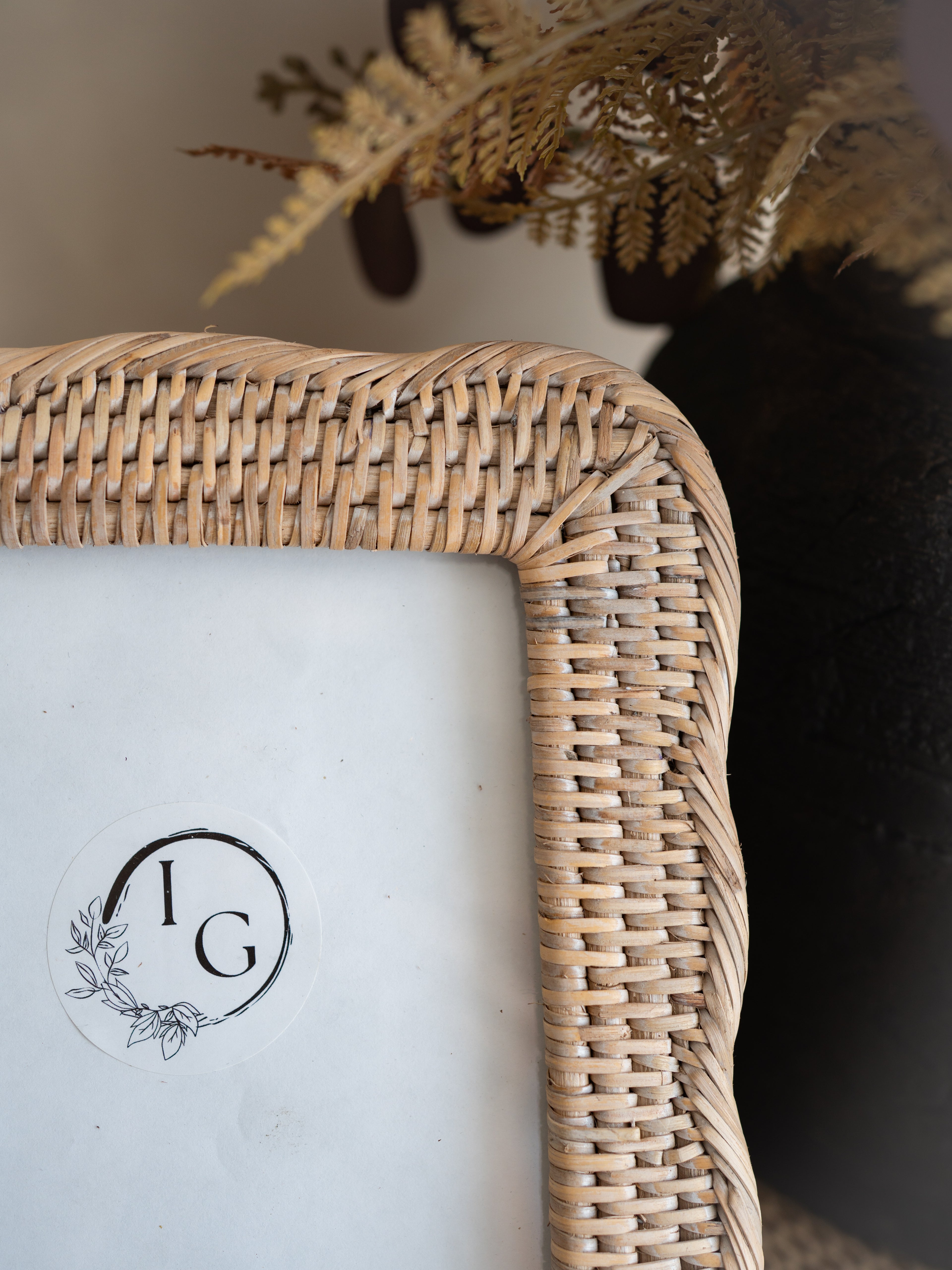 Close-up of a woven natural rattan picture frame corner with a white insert and a circular &