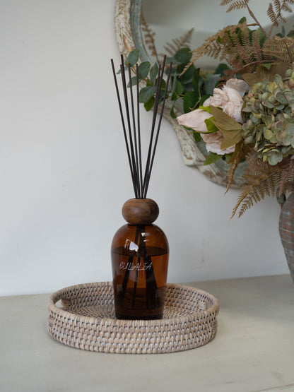 white washed oval rattan tray with amber reed diffuser