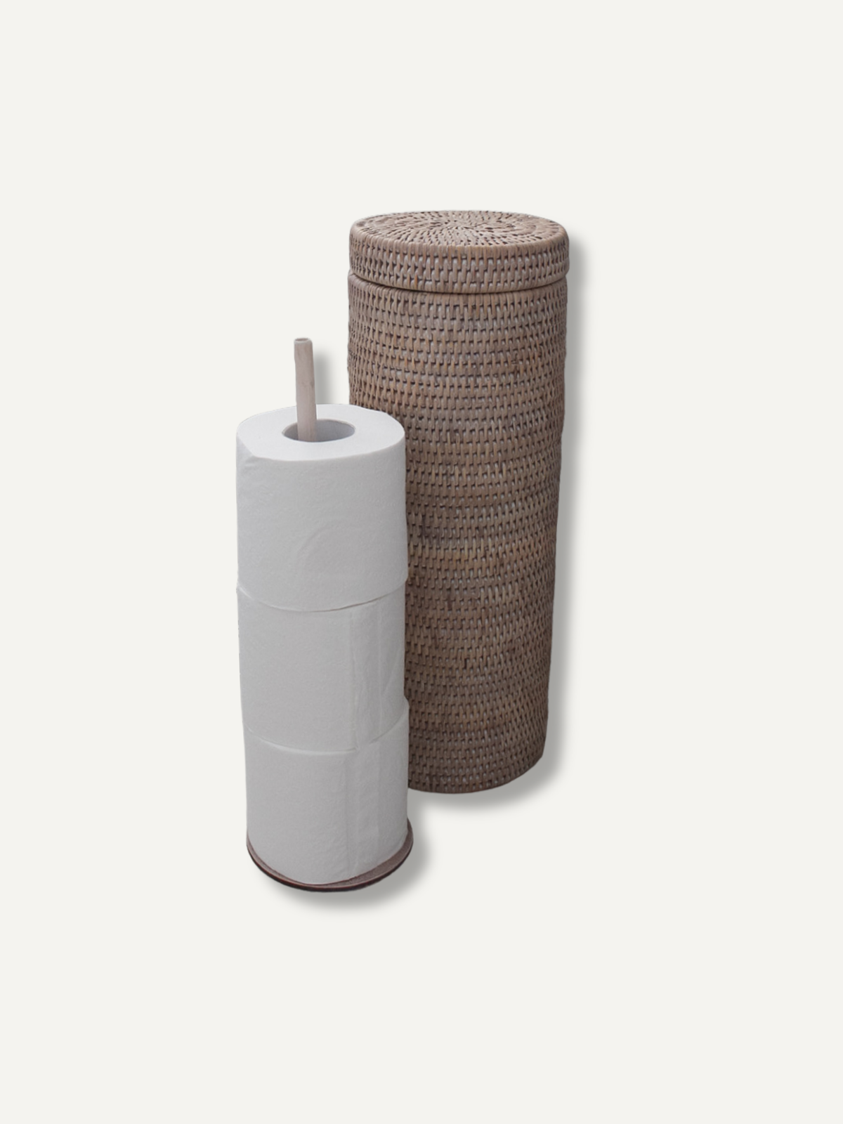 A tall cylindrical woven storage basket with a lid in a natural brown tone, standing next to a white toilet paper holder filled with toilet paper, on a light off-white background.