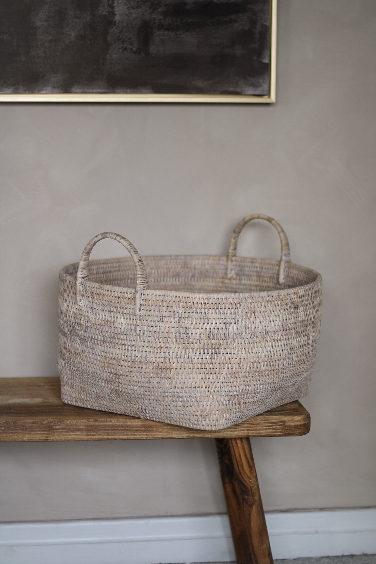 Woven basket on a wooden bench against a plain wall