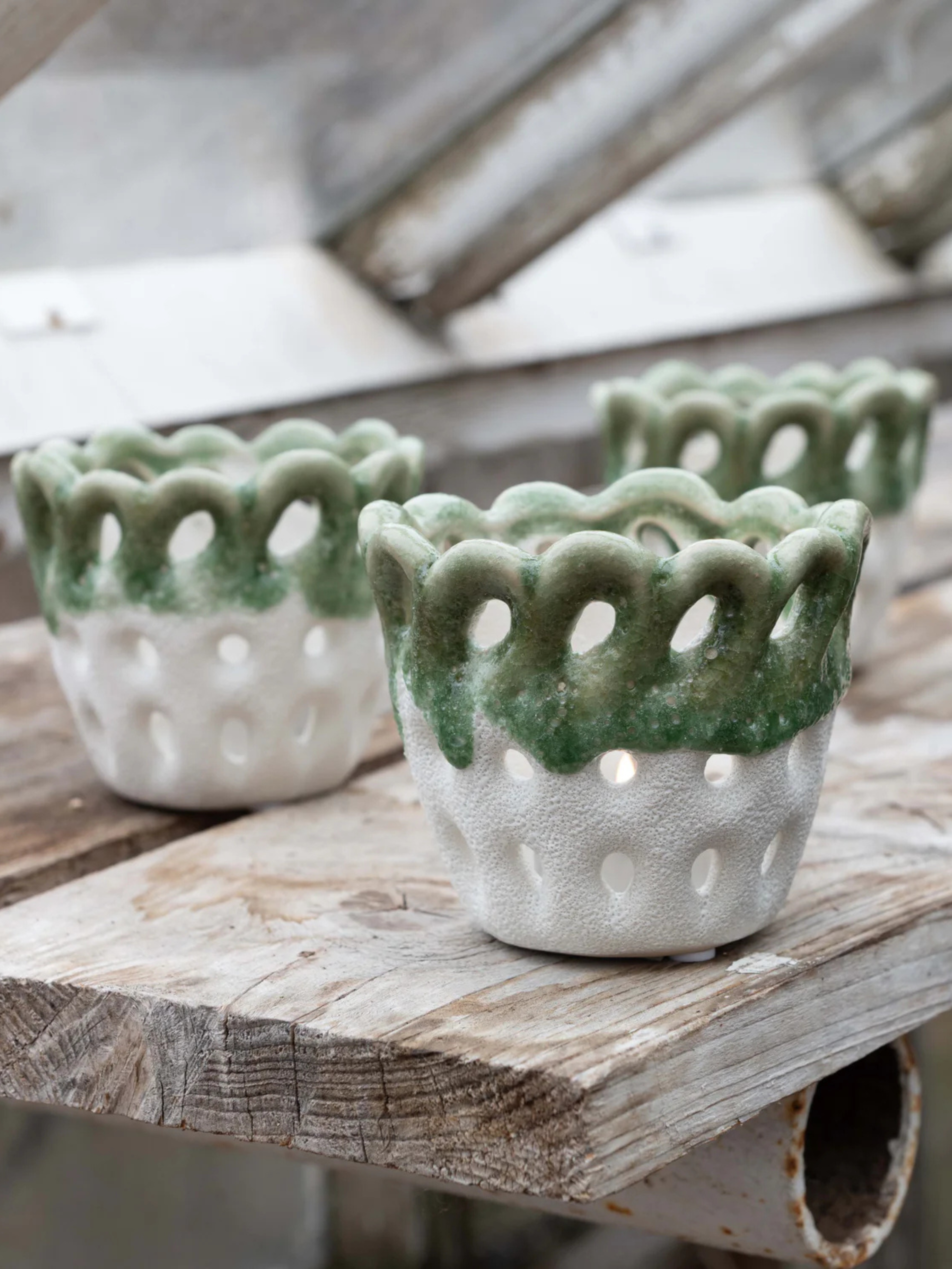 Three stoneware candle holder with green tops on a wooden surface, a lovely addition to your home decor