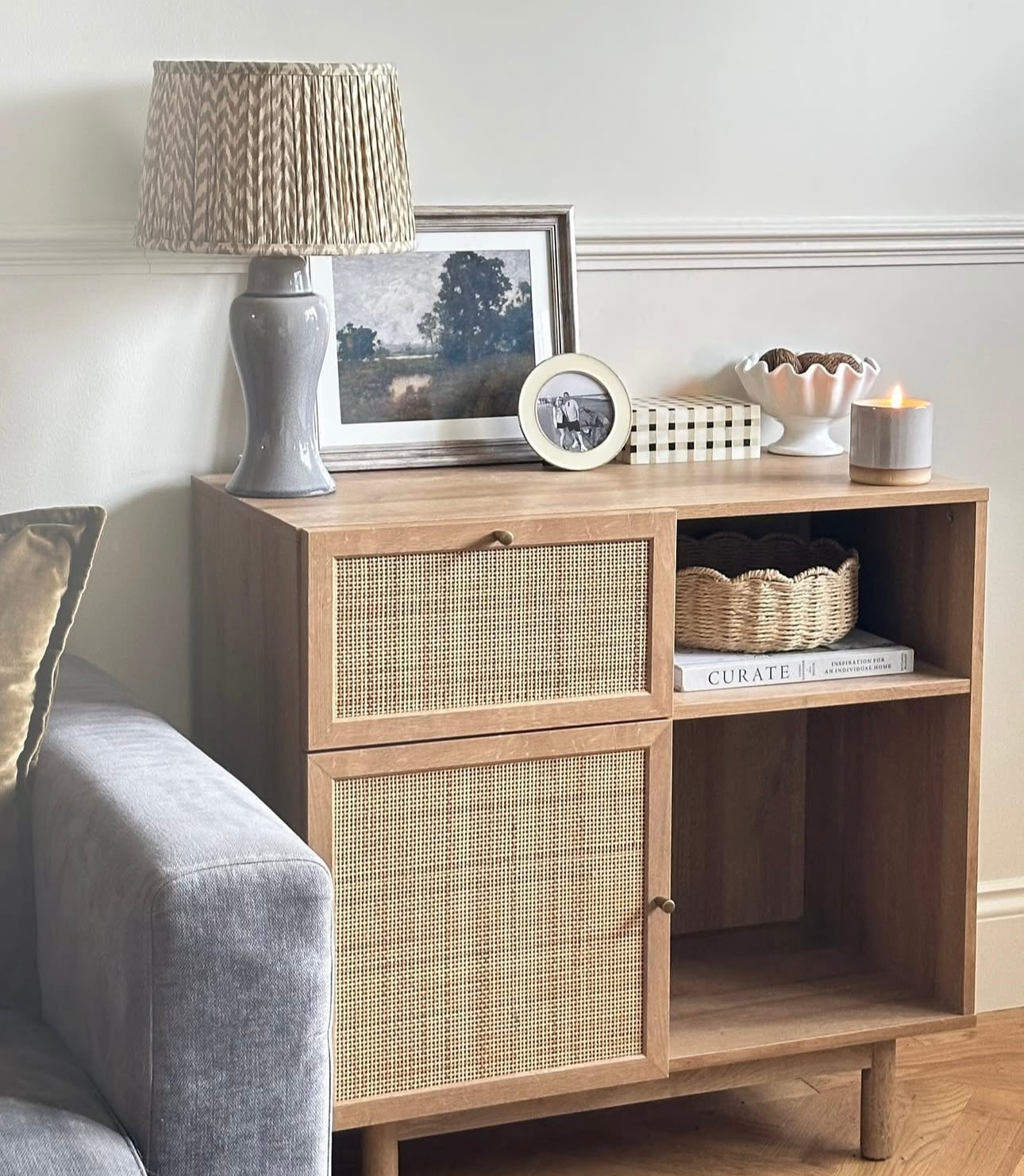 Wooden sideboard styled with lamp, photos, candle and white ruffled bowl