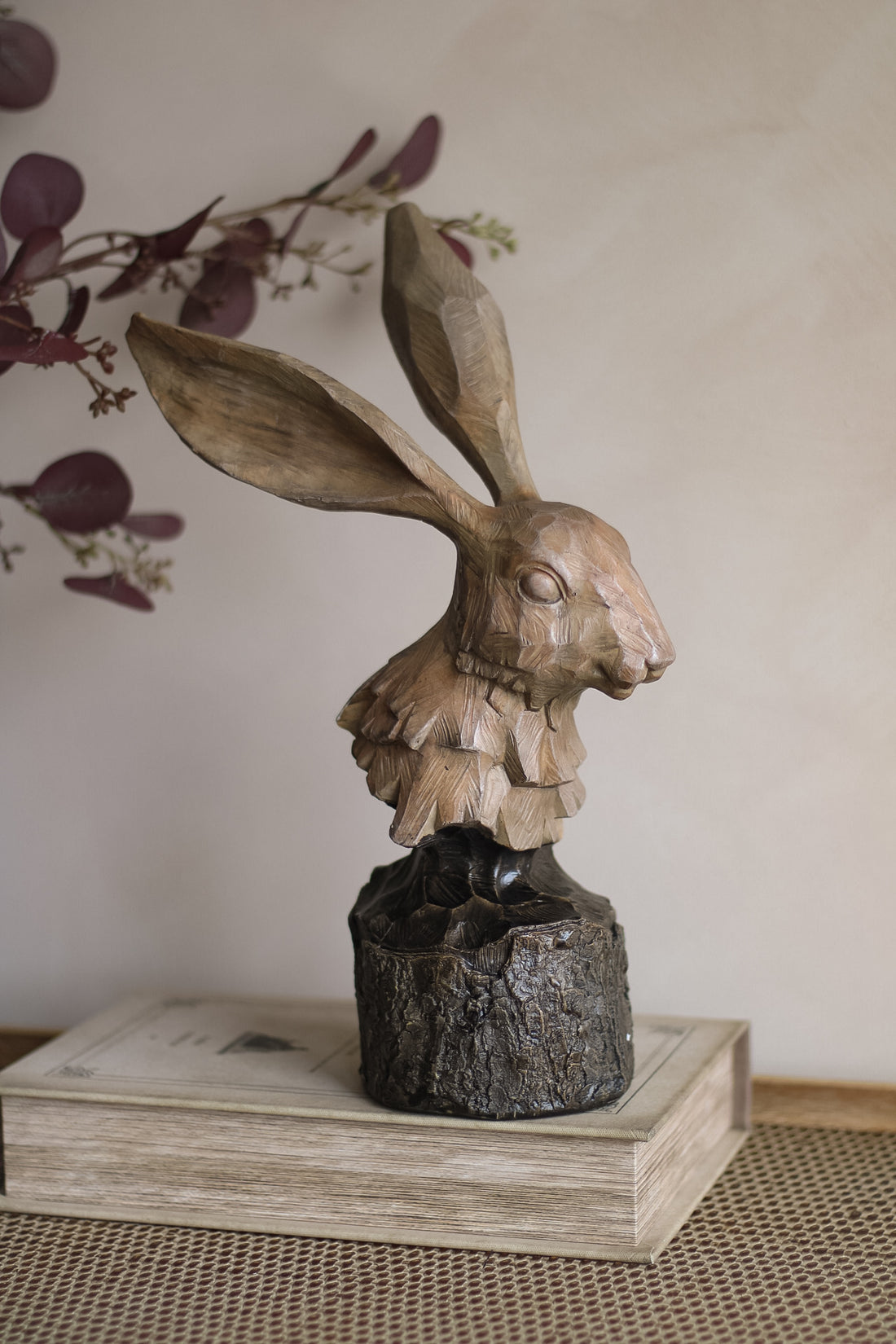 Wooden hare sculpture on a pedestal with a neutral background