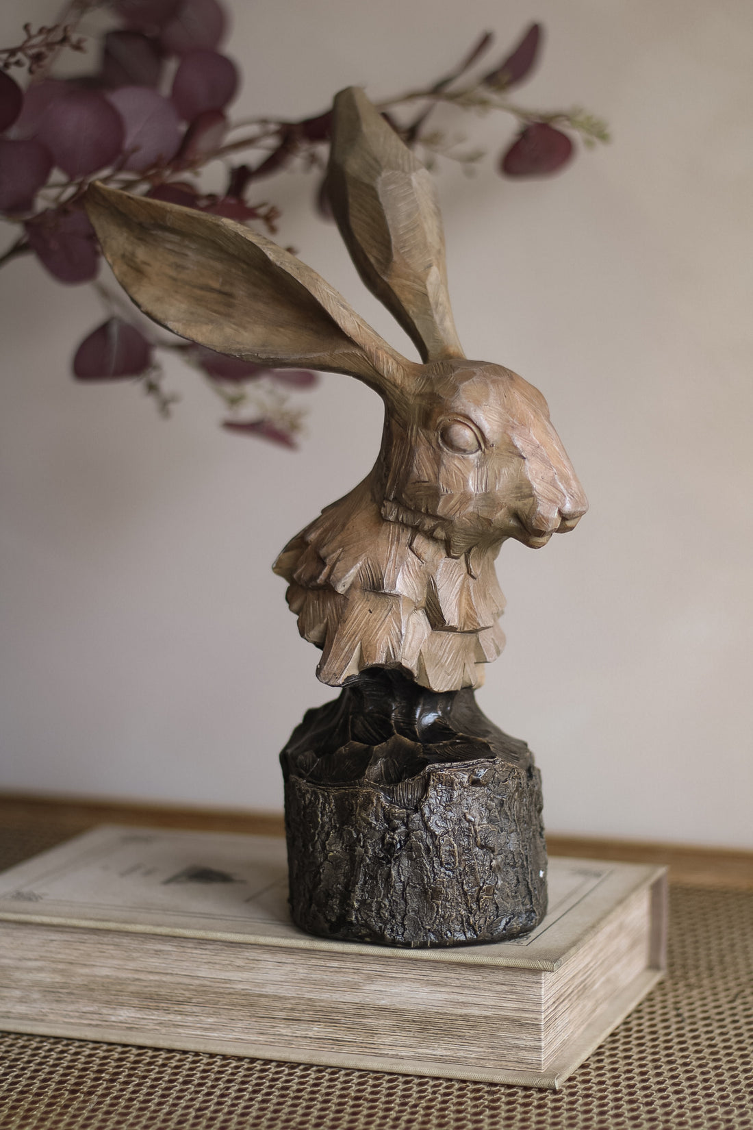 Wooden hare sculpture on a book with a blurred floral background